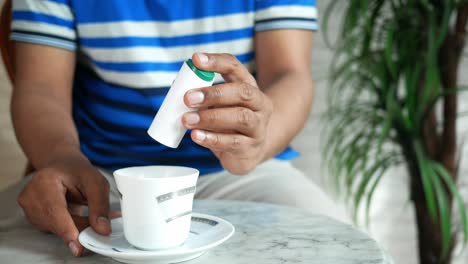persona que añade azúcar al café