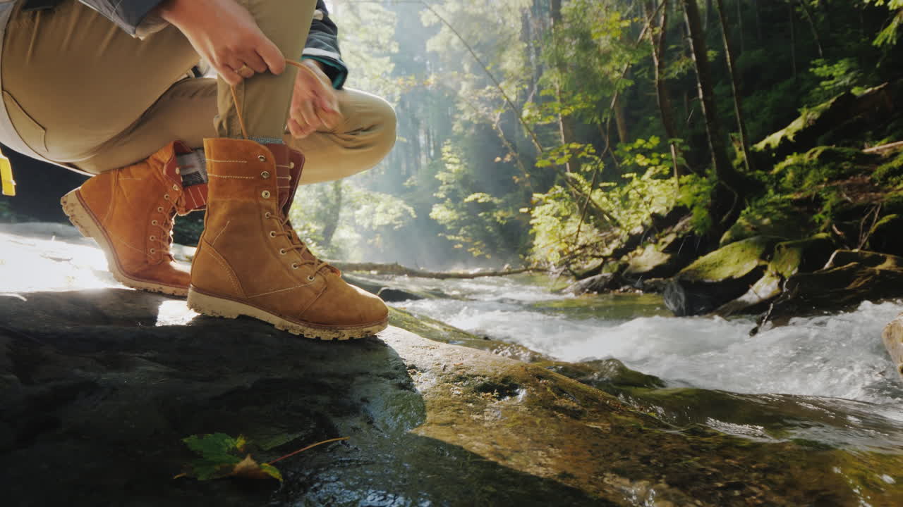 Female Hands Lace Up The Female On A Trekking Boot In The Forest In The Background A Mountain River 