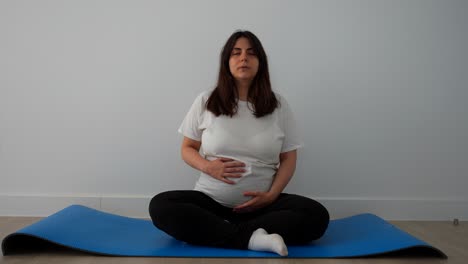 pregnant woman doing breathing exercises on a blue mat at home