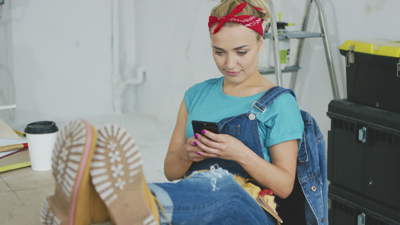 mujer sonriente usando un teléfono inteligente sentado en un banco de trabajo