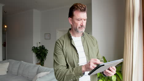 senior man using tablet at home, focusing on digital tasks
