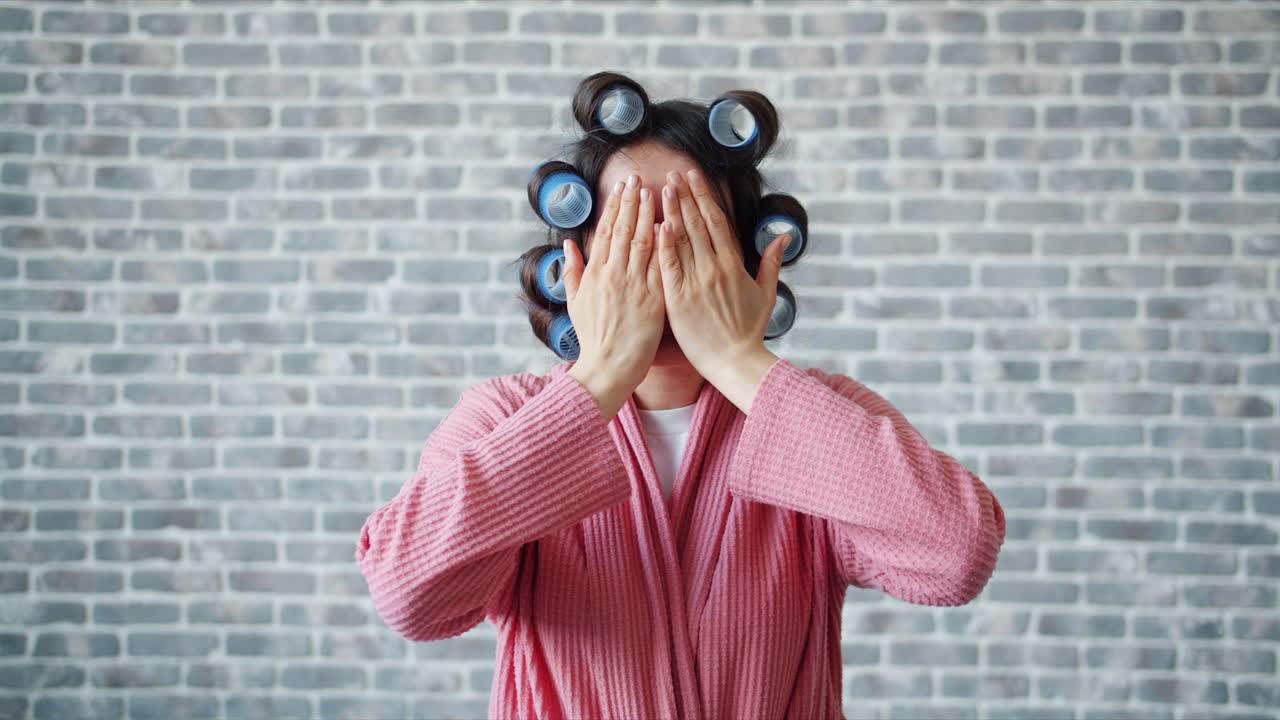 Woman in pink robe with hair rollers