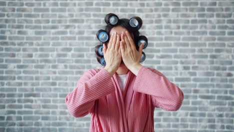 woman in pink robe with hair rollers