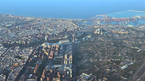 an spinning aerial view of valencia city center, coast and harbor. footage taken from an airplane cockpit departing from the airport at sunset.