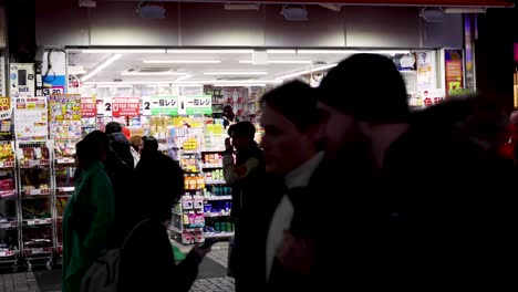 crowd of people walking past a brightly lit store