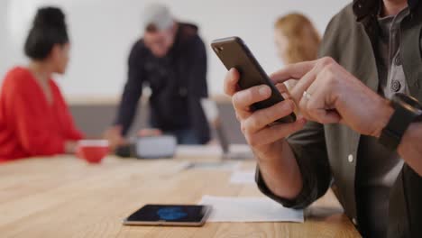 hombre caucásico usando un teléfono inteligente en una oficina creativa