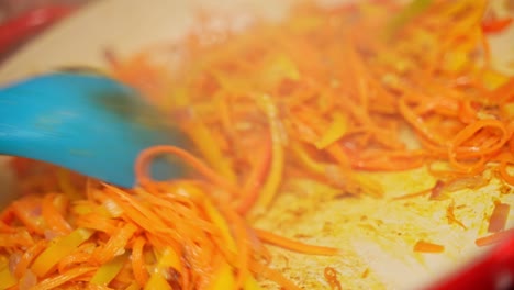 sliced orange bell paper stirred using wok spatula by chef.