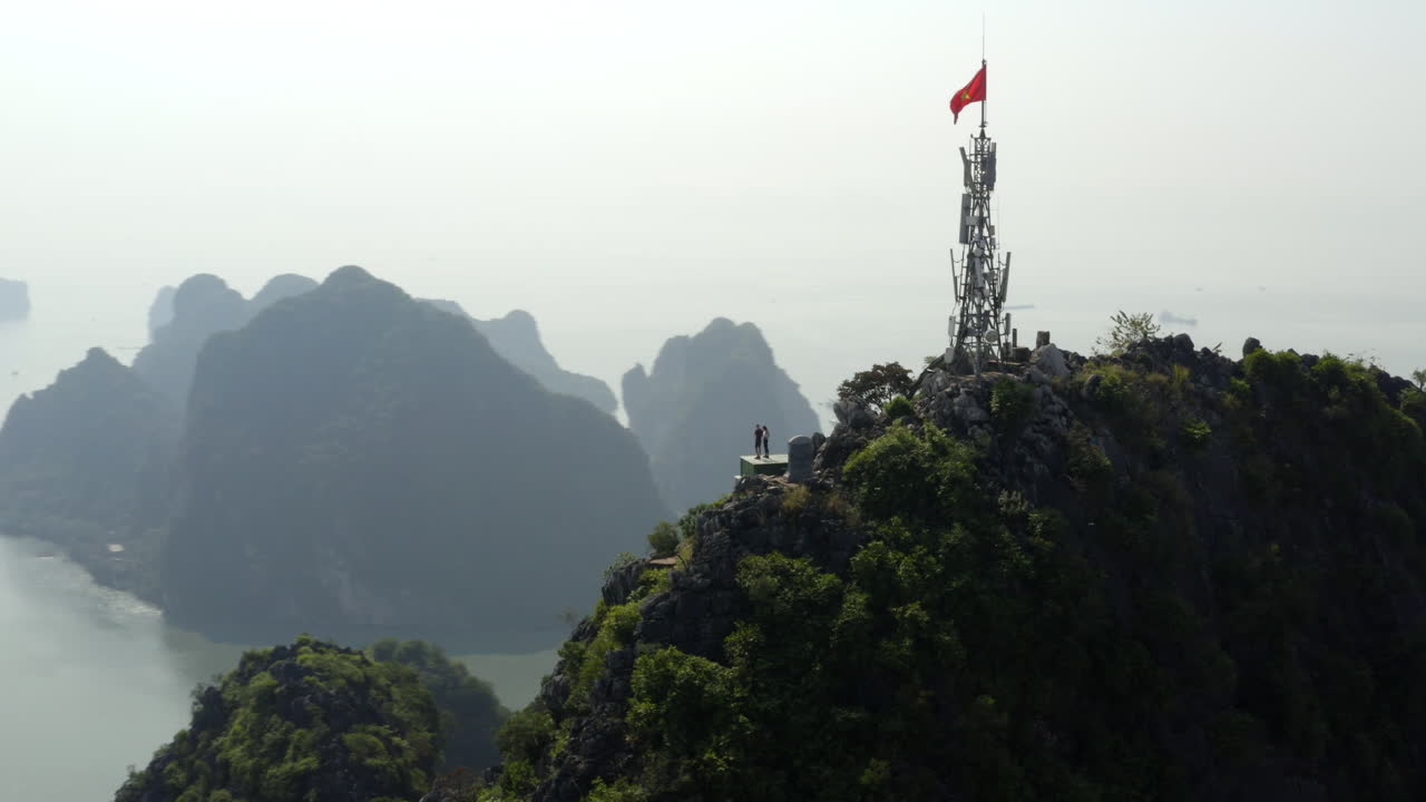 Panoramic aerial orbit of a communication tower, Bai Tho Mountain overlooking mist shrouded Halong Bay