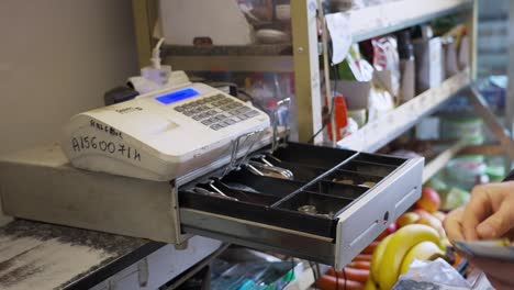 manos administrando una caja registradora durante una transacción de pago en una pequeña tienda
