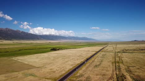 Highway-through-rural-mountain-farmlands-during-the-fall,-aerial