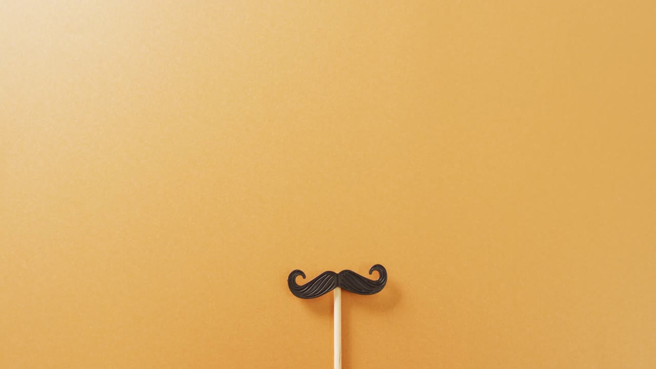 Video of false moustache on stick on yellow background with copy space