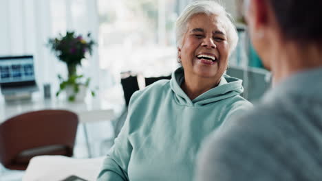 una anciana sonríe y se ríe mientras habla con su médico en un hospital.