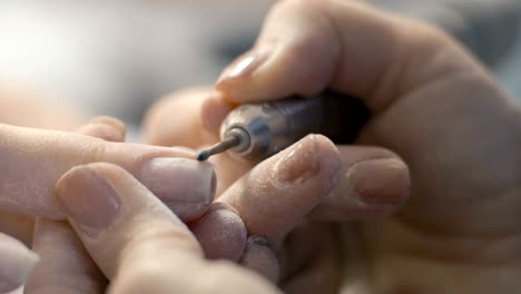 extreme close-up, manicure master handles nails on the customer's hand finger after removing the layer of old lacquer