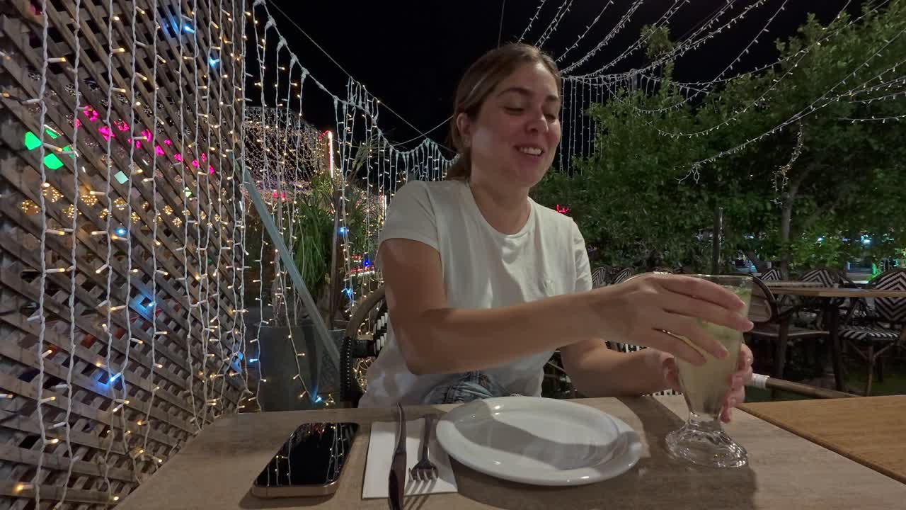 Smiling Woman Taking a Selfie with Her Cocktail at Night