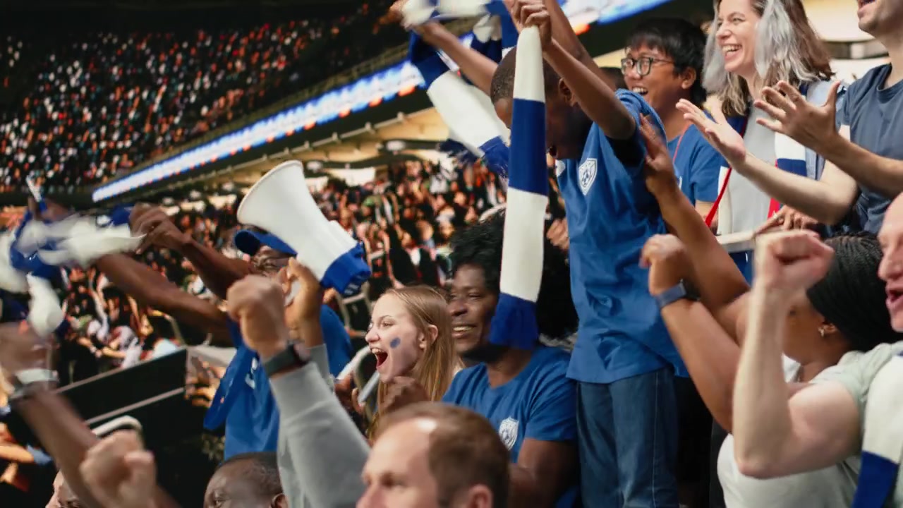 Joven aficionado infantil celebra con hinchas de fútbol azules animando en el estadio.