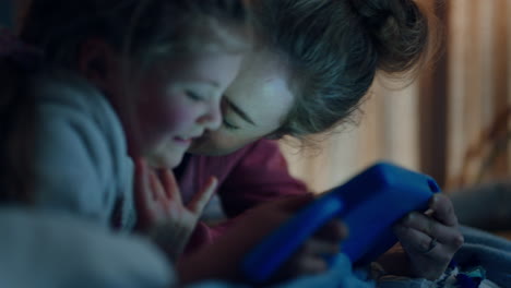 madre e hijo usando una computadora tablet madre enseñando a una niña pequeña jugando juegos en tecnología de pantalla táctil divirtiéndose antes de acostarse