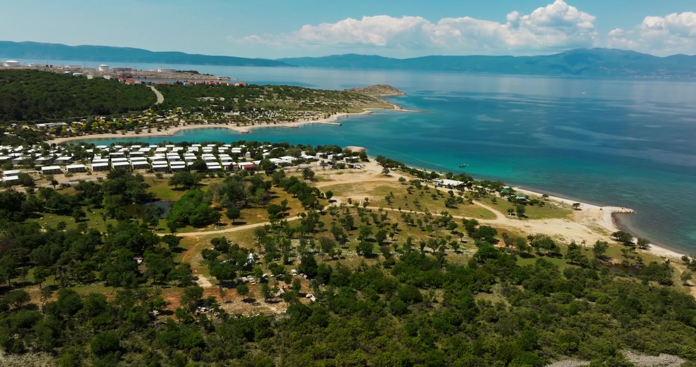 Panorama aereo con drone di un moderno resort balneare con spiagge, case mobili e il turchese Mare Adriatico lungo la costa croata durante una soleggiata giornata estiva