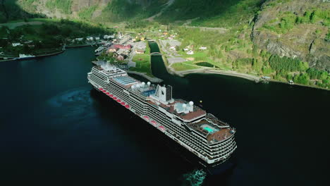 Massive-cruise-ship-docking-near-town-of-Flam-in-Aurland,-Norway,-aerial-view