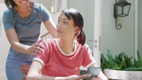 Happy-biracial-sisters-embracing-and-smiling-in-garden,-in-slow-motion