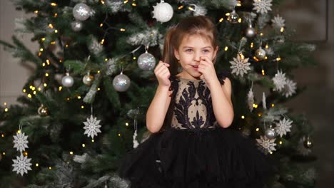 girl playing with confetti near christmas tree