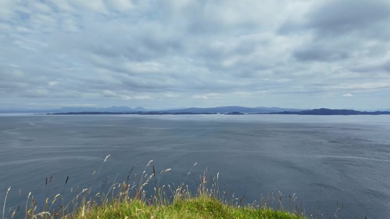 Dynamische Zeitrafferaufnahme eines ruhigen Meeres an der Küste der Isle of Skye im ursprünglichen Schottland an einem bewölkten Tag