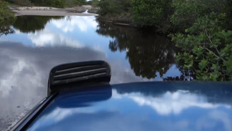 coche todoterreno atravesando un gran charco, casi sumergiéndose en él.
