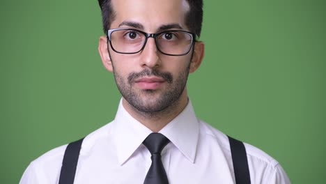 joven empresario persa barbudo y guapo contra un fondo verde