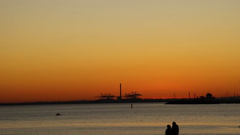 couple silhouetted against sunset at st kilda beach