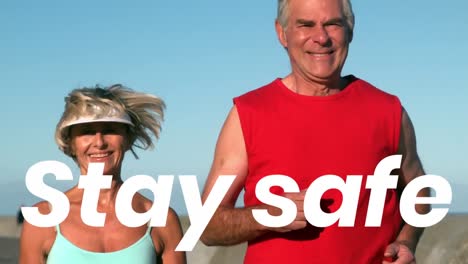 Animación-Del-Texto-Stay-Safe-Sobre-Una-Pareja-De-Ancianos-Corriendo-En-La-Playa