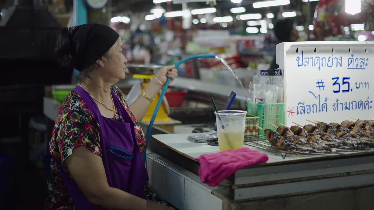 Woman preparing grilled fish at a street market