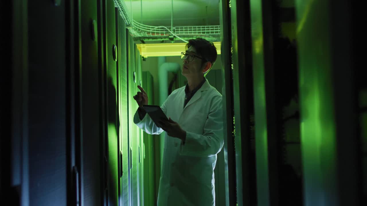 Tecnico IT asiatico in camice da laboratorio che usa un tablet per controllare un server di computer