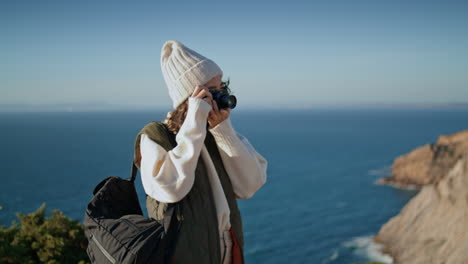 tourist hiking make picture at ocean cliff. happy girl admire mountain landscape