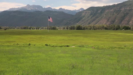 large american flag waving in the wind over a meadow with the san juan mountains in background