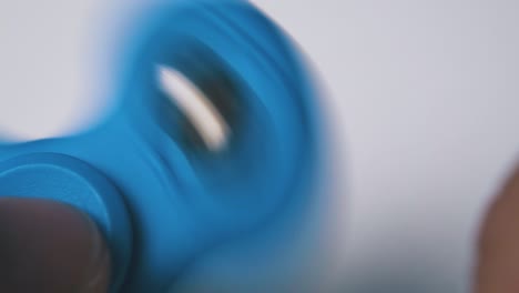 young man holds blue spinner with ball on light background