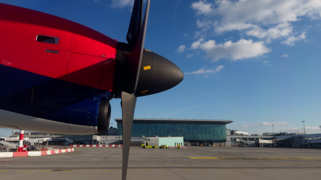 Primo piano del motore di un aereo turboelica con elica in rotazione che rulla sul piazzale dell'aeroporto prima del decollo. Aereo regionale che si prepara alla partenza sotto un cielo azzurro limpido presso un terminal moderno.