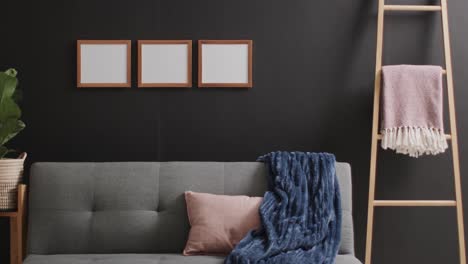 Three-wooden-frames-with-copy-space-on-white-background,-sofa-and-plant-and-black-wall