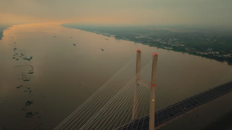 bridge over river in vietnam at sunset with warm sky and water reflections