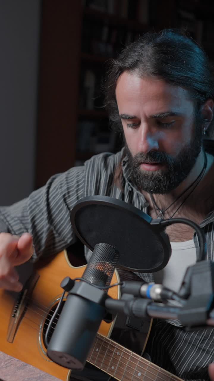 Man adjusting a pop filter in front of a microphone and acoustic guitar