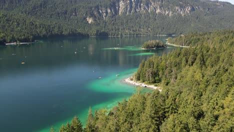 claro lago verde sereno rodeado de espesa agua de bosque de hoja perenne y el follaje verde aprecian el entorno tranquilo uno de los barcos en el lago parece estar flotando boca abajo por la orilla