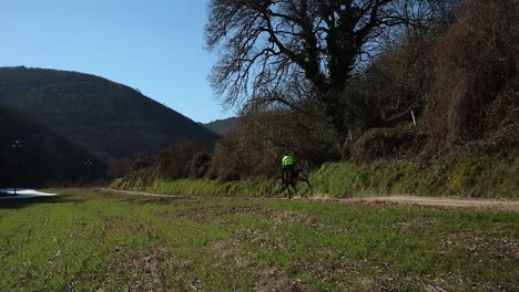 caucasian man in yellow jilet rides a horse that runs fast in the countryside, slow motion scene