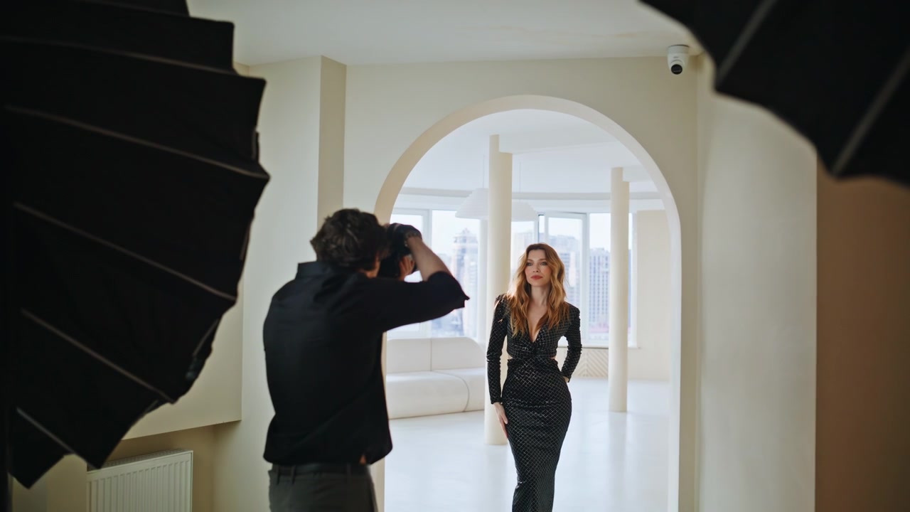 Fotoshoot backstage i luksuslejlighed. Fotograf instruerer model i sort kjole