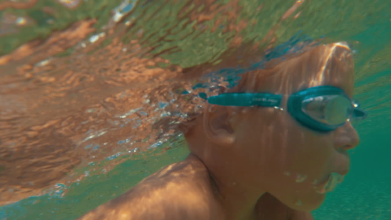 용감한 작은 소년이 물 에서 수영하고 있습니다.