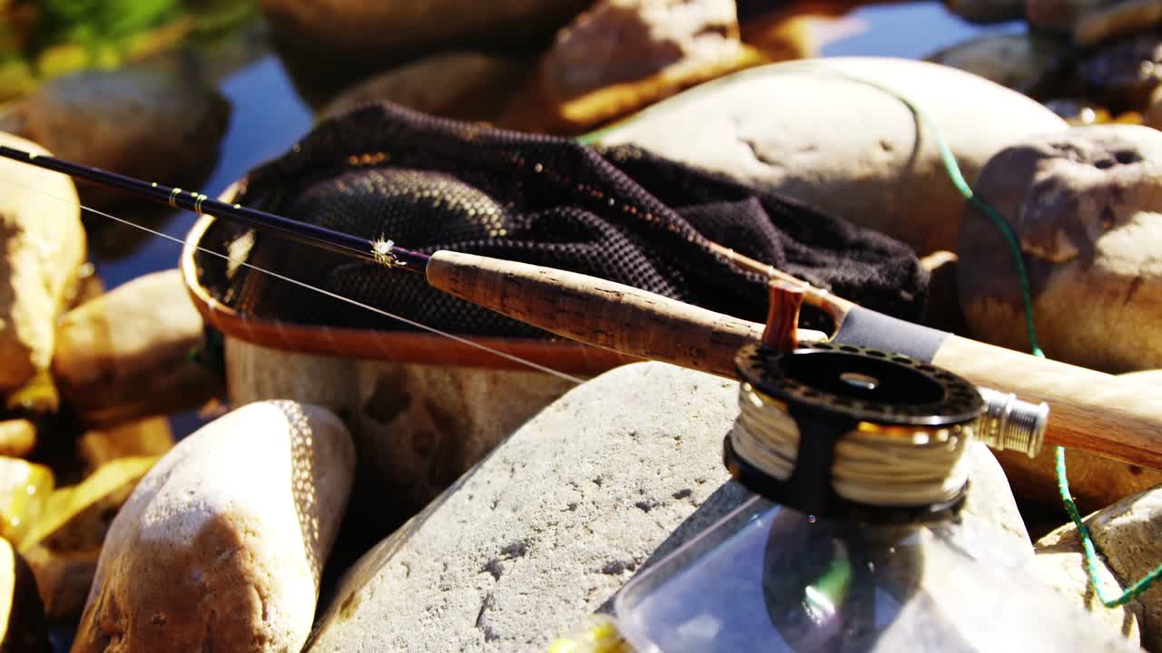 Canna da pesca a mosca, mulinello e scatola per l'attrezzatura da pesca su una roccia