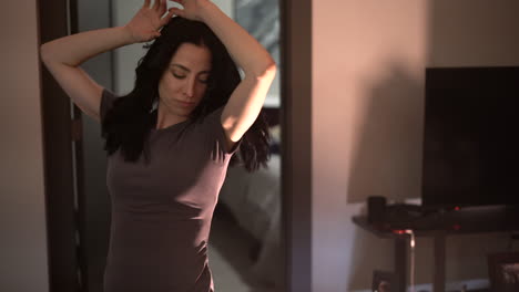 young attractive woman having fun dancing and singing in her apartment alone - looking straight into the camera - gimbal shot