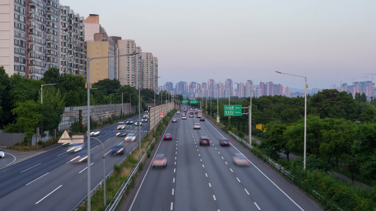 Time-lapse of Gangbyeonbuk-ro highway in Seoul at sunset, with moving traffic and tall apartment buildings in view