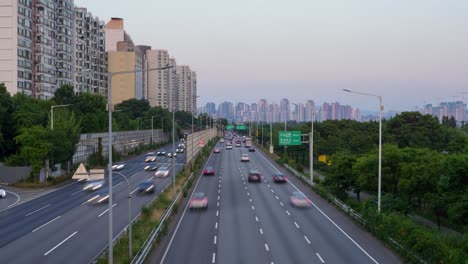 time-lapse of gangbyeonbuk-ro highway in seoul at sunset, with moving traffic and tall apartment buildings in view