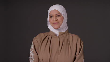 retrato de estudio de una mujer musulmana sonriente con hijab contra un fondo oscuro 1