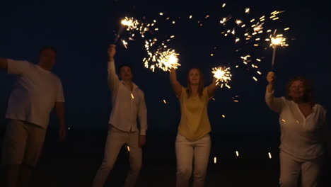 Familie-Mit-Wunderkerzen-Am-Strand-In-Der-Nacht