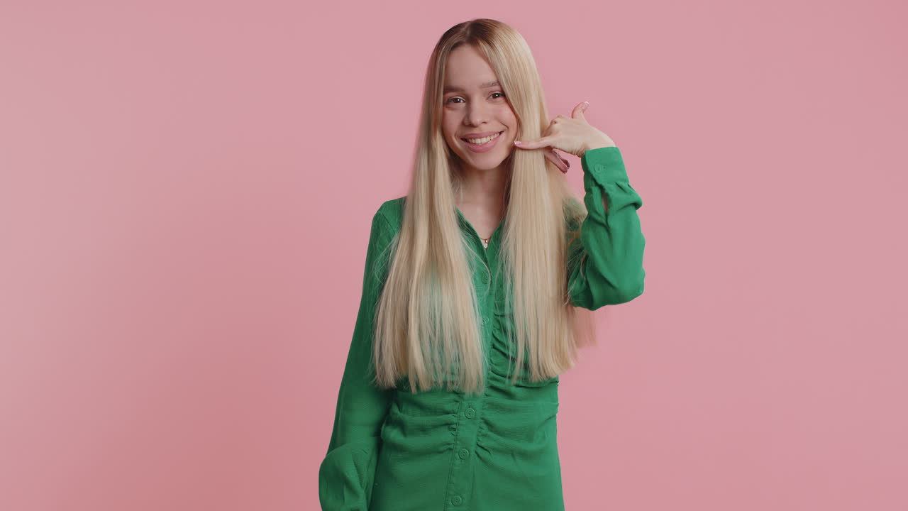 Teen young woman looking at camera doing phone gesture like says hey you call me back conversation