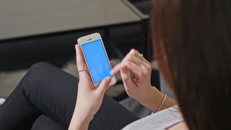mujer sostiene un teléfono inteligente con pantalla azul